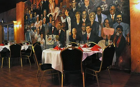 Dining tables beside a wall mural.