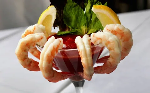 Shrimp cocktail with lemon and cocktail sauce.