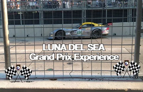 Silver race car passing a grandstand.