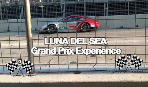 Red race car passing a grandstand.